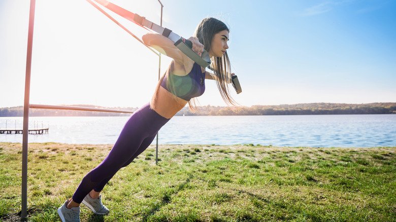 femme faisant des pompes avec un appareil de suspension