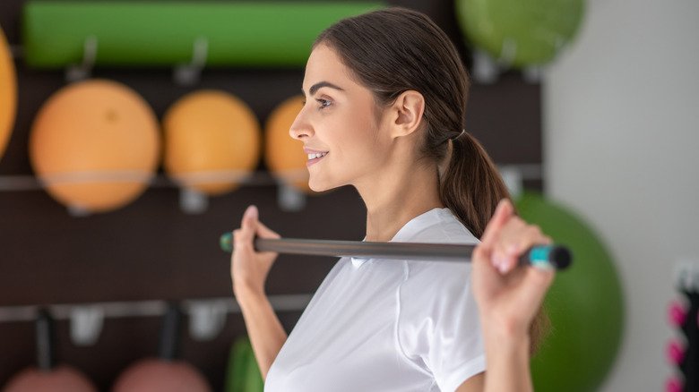 Femme utilisant un bâton pour étirer ses épaules