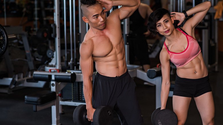 couple faisant des flexions latérales avec des haltères