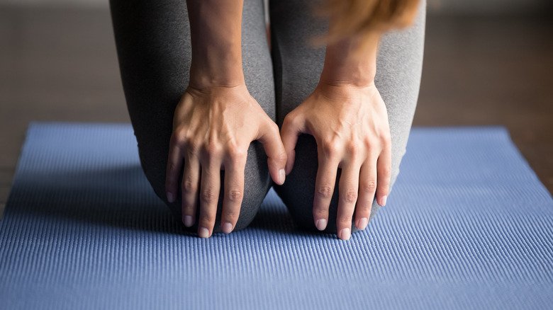 personne tenant les genoux sur un tapis de yoga