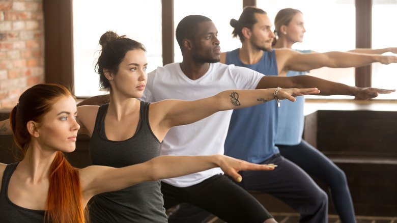 groupe d'étudiants de yoga faisant la pose du guerrier 2