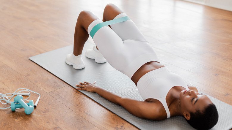 femme faisant la pose du pont en utilisant une sangle