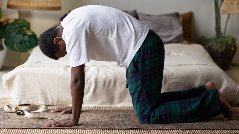 homme faisant la pose du chat/vache