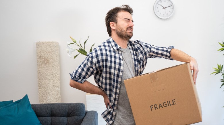 Un homme souffre après avoir soulevé une lourde boîte