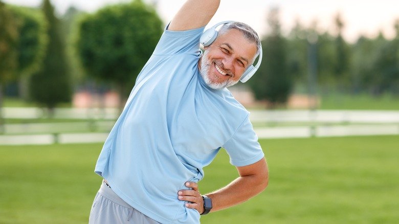 homme souriant s'échauffant à l'extérieur