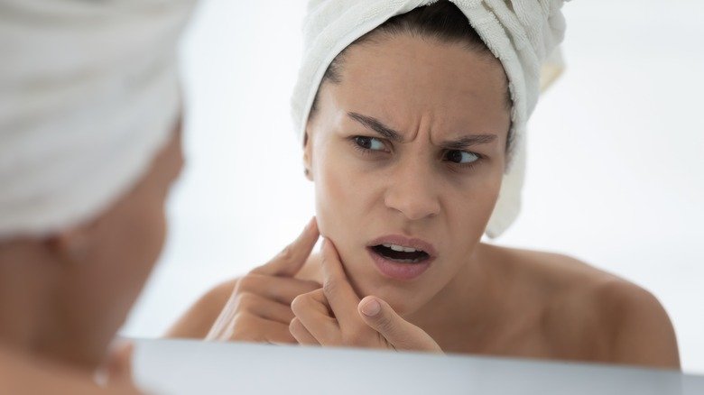 Une femme bouleversée regarde sa peau dans le miroir