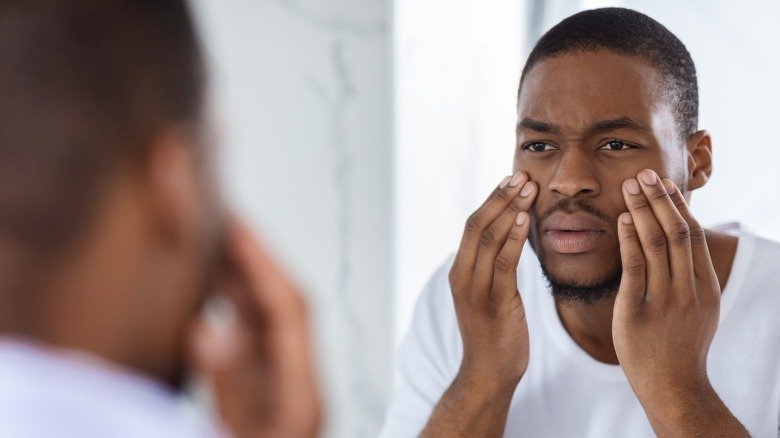 Homme examinant sa peau dans un miroir