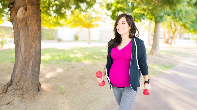 une femme enceinte portant des poids et marchant