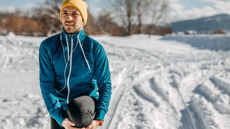 homme agenouillé dehors dans la neige en hiver