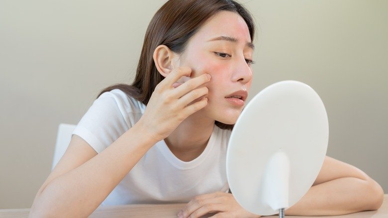 femme regardant sa peau dans le miroir