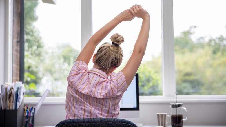 Une femme s'étire à son bureau