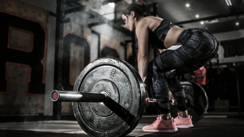 Une femme fait du soulevé de terre dans une salle de sport