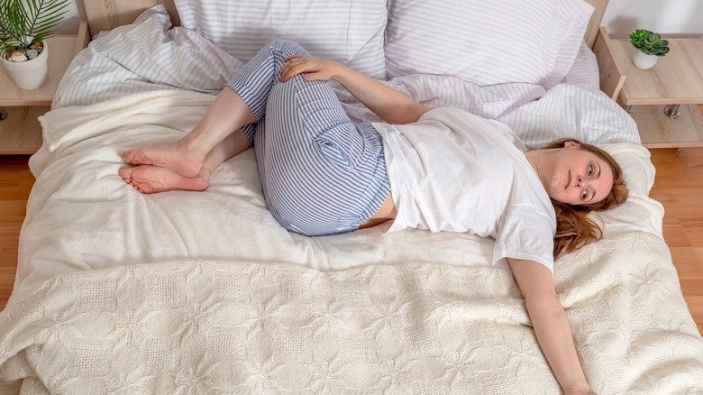 Femme effectuant une torsion de la colonne vertébrale en position couchée sur le dos au lit