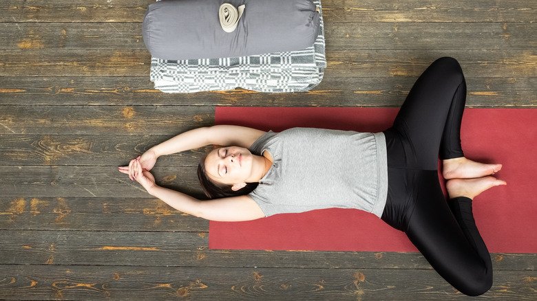 Femme allongée sur un tapis de yoga en position couchée sur le dos