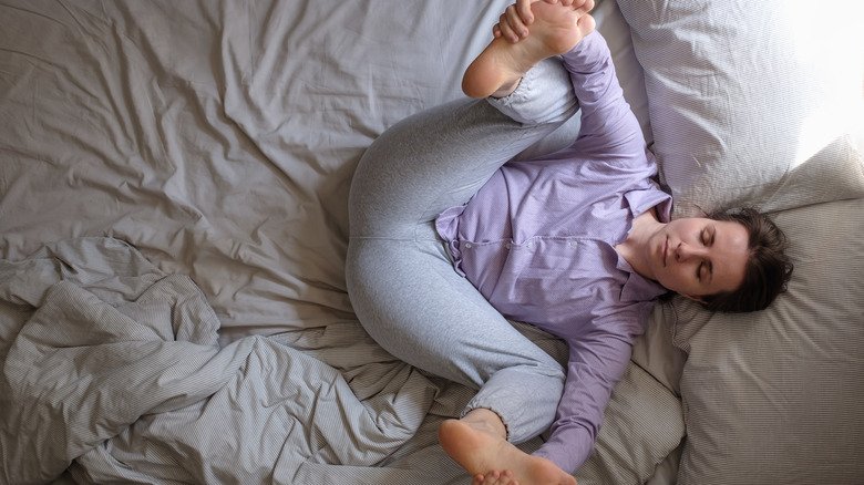 Une femme faisant la pose du bébé heureux au lit