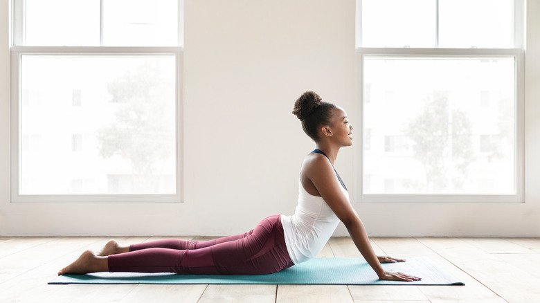 Femme faisant la posture du cobra sur un tapis de yoga