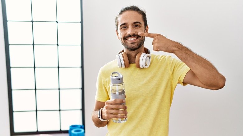 homme buvant de l'eau et pointant son visage