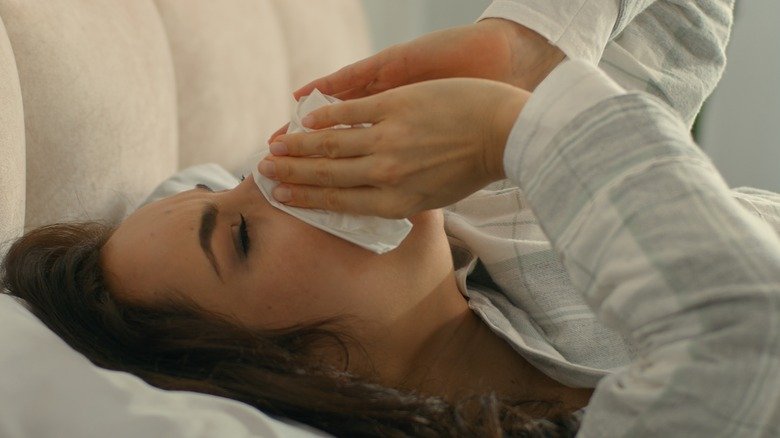 Femme allongée dans son lit se mouchant