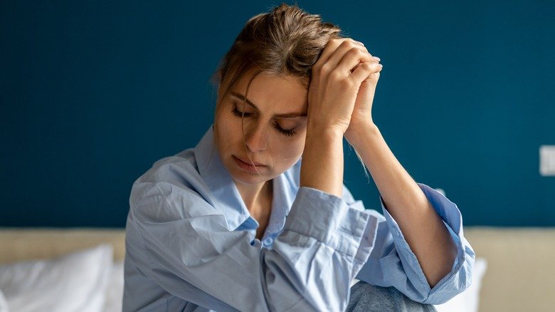 Femme assise dans son lit avec frustration