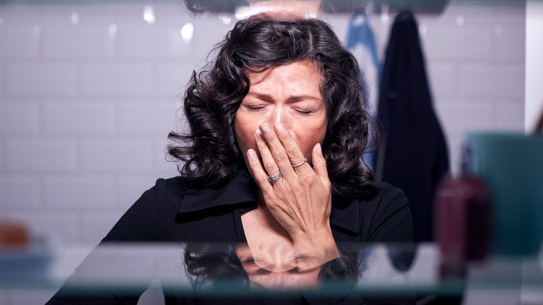 Femme bâillant devant le miroir de la salle de bain