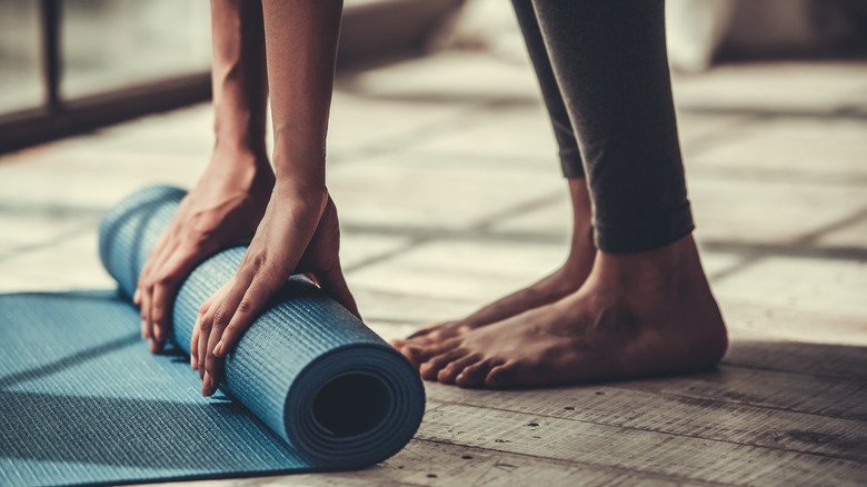 une femme déroule un tapis de yoga