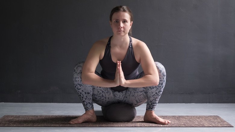 Femme assise faisant la pose de la guirlande