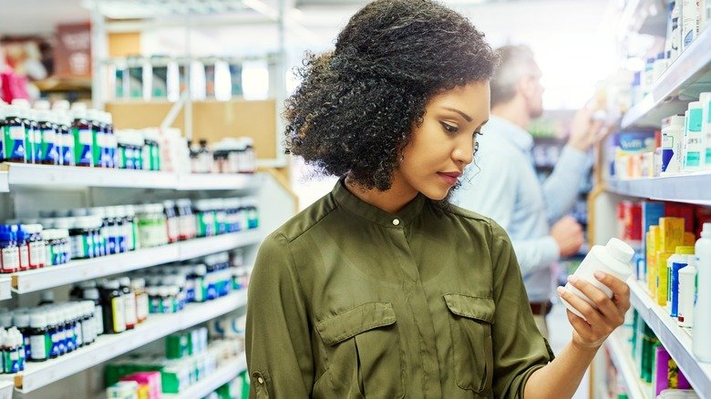 Femme regardant l'étiquette d'un médicament