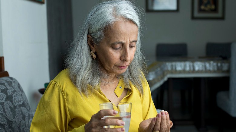 Une femme âgée prend des médicaments avec de l'eau