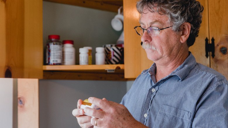 un homme plus âgé regarde attentivement ses médicaments