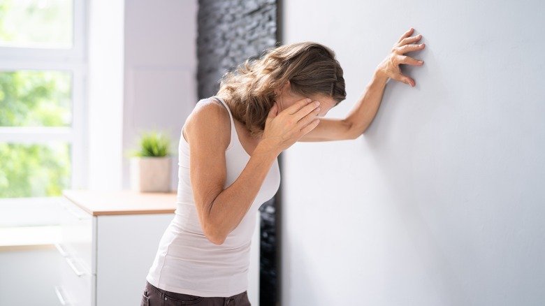 Femme étourdie appuyée contre un mur