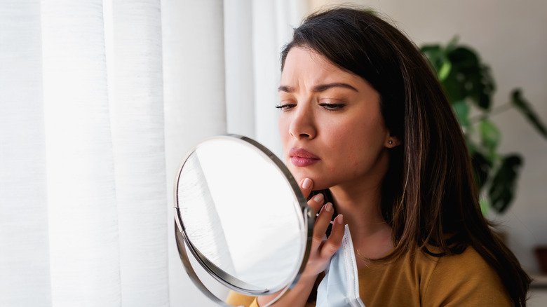 Femme regardant un bouton dans le miroir