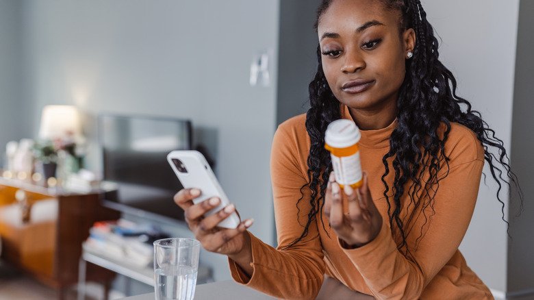 Femme regardant un flacon de médicament