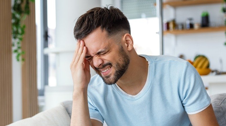 homme grimaçant de douleur à la tête