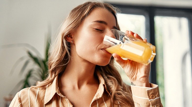 Femme souriante et buvant un verre de jus