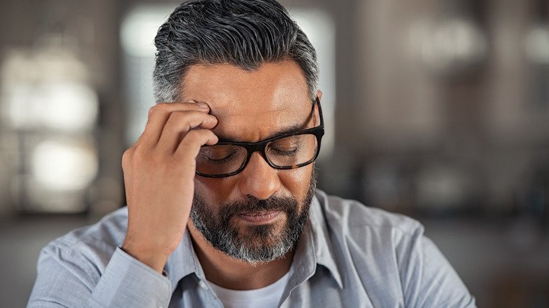 Homme stressé tenant sa tête à la main