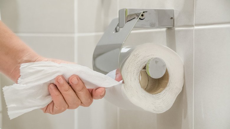 Main retirant le papier toilette du rouleau