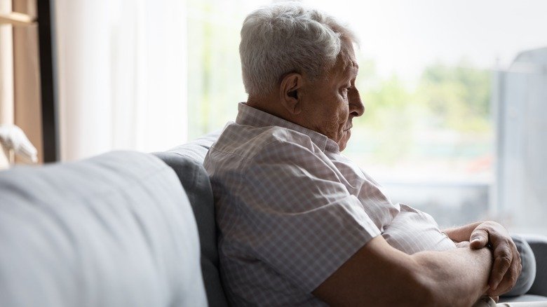 Homme âgé triste assis sur un canapé