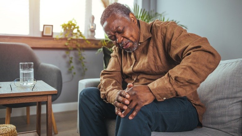 Un homme âgé se tient le genou en raison de la douleur