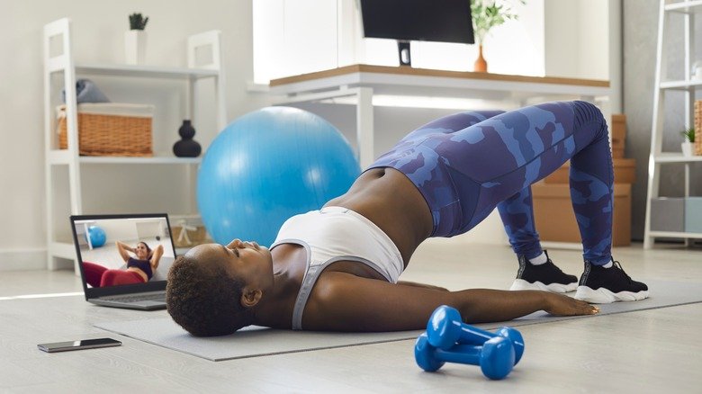 femme faisant du yoga à côté d'un ordinateur portable