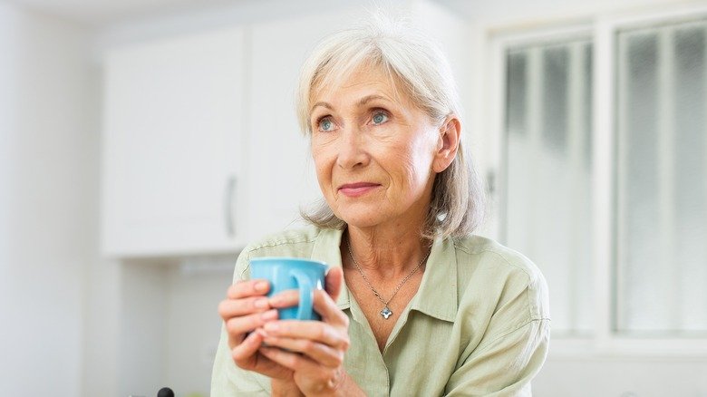 femme tenant une tasse tout en regardant au loin