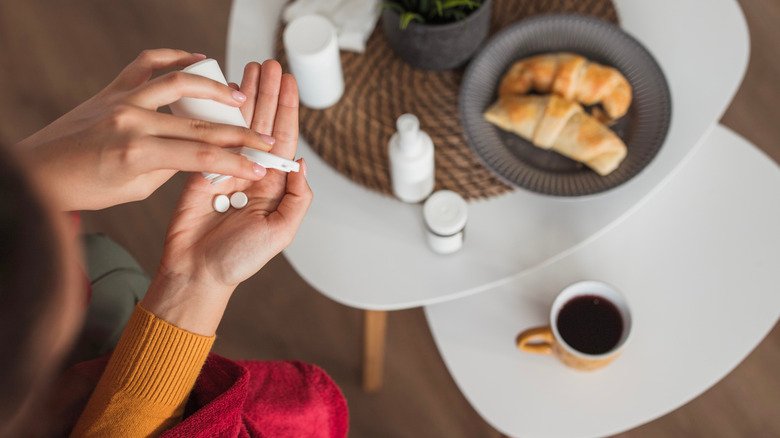 Femme prenant des pilules avec du café