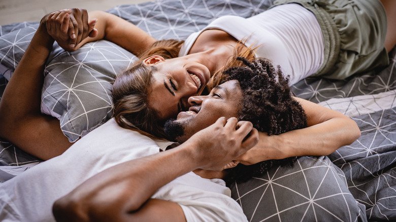 Couple souriant allongé dans son lit