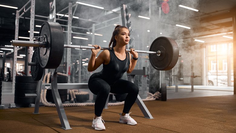 Femme faisant des squats arrière avec une barre