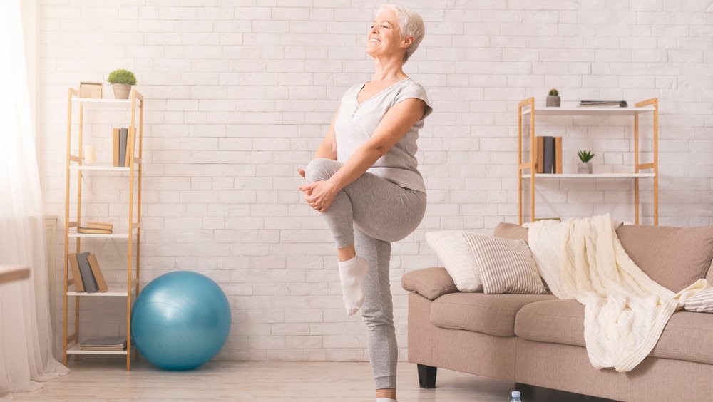 Une femme âgée fait du yoga à la maison