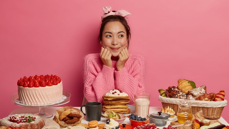 Une femme entourée de gâteaux et de desserts