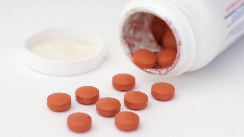 bouteille de comprimés d'ibuprofène renversée sur la table