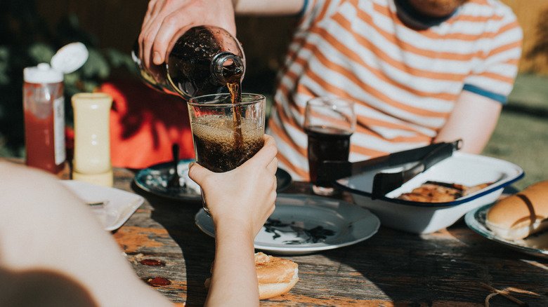 personne versant un soda lors d'un pique-nique