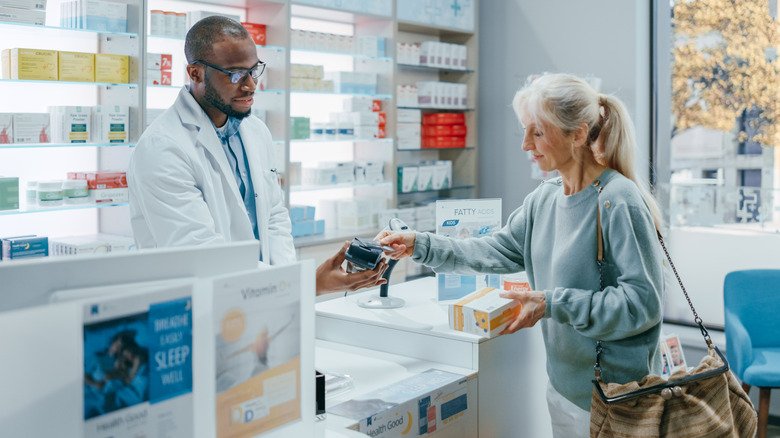 femme payant ses médicaments à la pharmacie