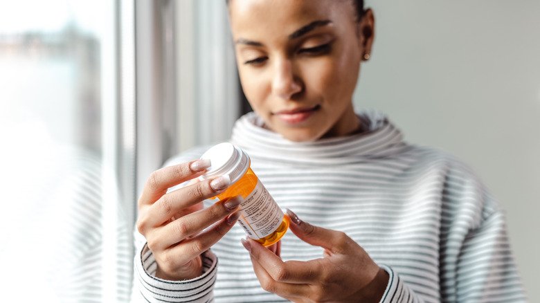 Femme regardant un flacon de médicament