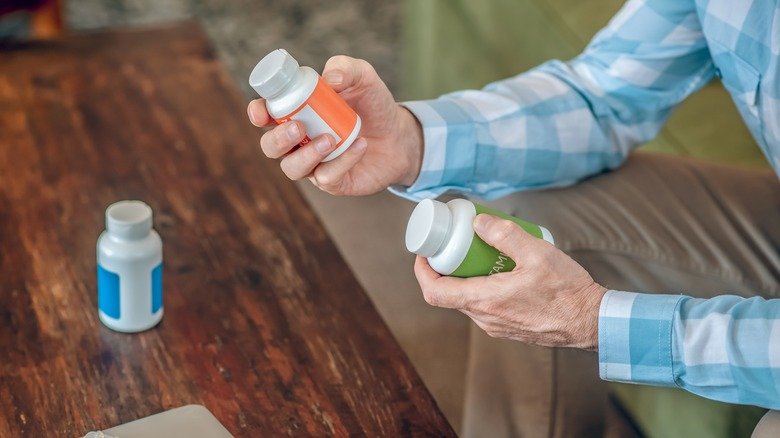 les mains d'un homme tenant des bouteilles de suppléments